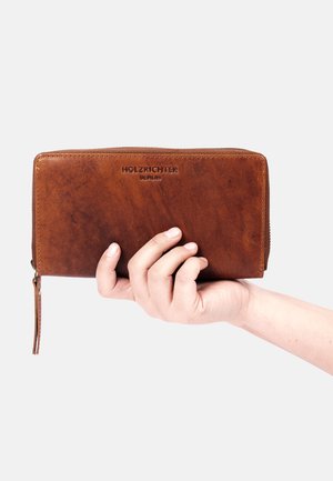 Brown leather wallet with a zip-around design, embossed "HOLZRICHTER BERLIN," and a textured surface held in a hand.