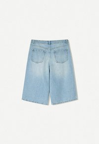 Světle modré džínové šortky s volným střihem, s dvěma zadními kapsami a roztřepenými okraji nohavic. Tkanina působí měkce a lehce vybledle.