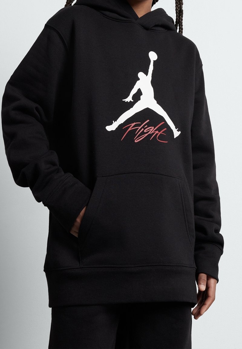 Czarna bluza z kapturem zdobiona białym logo Jumpman i czerwonym napisem „Flight”. Wykonana z miękkiego materiału, posiada kieszeń z przodu oraz ściągacze na mankietach.