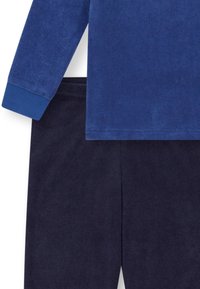 Blaues Langarmhemd mit gerippten Bündchen, kombiniert mit navyfarbener Cordhose. Beide Teile haben eine strukturierte Oberfläche und wirken weich.