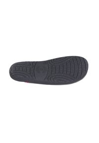 Suela de zapato de goma negra con patrones de agarre texturizados y forma curva, con un acento rosa en el talón y un detalle de logo circular.