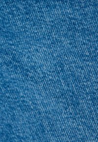 Tela de mezclilla azul con un tejido de sarga, que presenta una textura suave y un leve patrón diagonal, mostrando sutiles variaciones en el color.