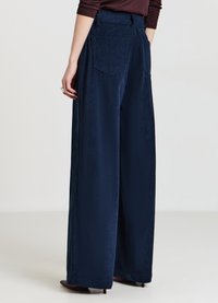 Pantaloni larghi in velluto a coste blu navy scuro con costine verticali, dotati di due tasche posteriori e una vita sagomata.