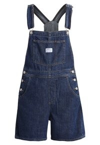 Shorts salopette en denim avec bretelles réglables, poche poitrine avant avec étiquette, poches latérales et fermetures à boutons sur les hanches.
