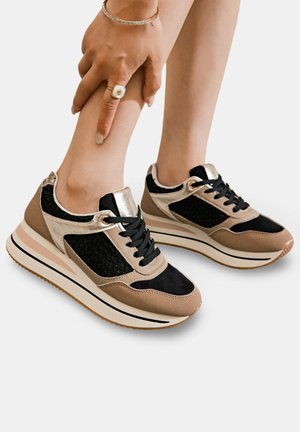 Baskets à lacets avec tige en maille noire et en suède synthétique, accents en métal doré, schéma de couleurs beige et noir, et semelle en caoutchouc épaisse.