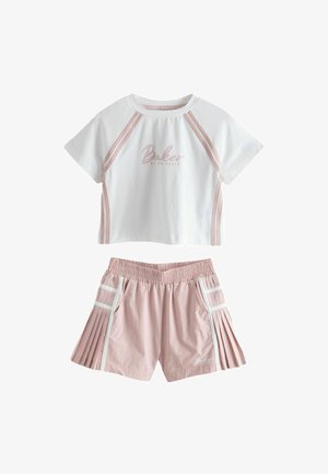Top corto bianco a maniche corte con righe rosa e scritta "Baker", abbinato a pantaloncini rosa plissettati con bordo bianco e vita elastica.