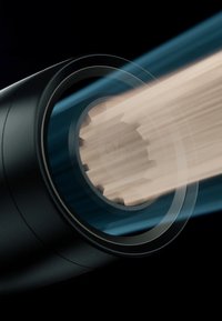 Gros plan sur des poutres en bois en cours de découpe ou de façonnage à l'intérieur d'une machine cylindrique noire en rotation, avec des morceaux de bois flous en mouvement.