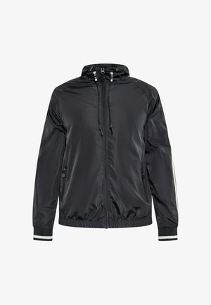 Chaqueta de nailon negra con capucha, puños elásticos y dos bolsillos frontales con cremallera. Presenta un detalle de rayas en contraste a lo largo de las mangas.