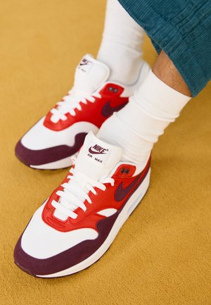 Nike Air Max sneakers med en hvid mesh-overdel, røde læderdetaljer, lilla suede-detaljering og en tyk hvid sål.
