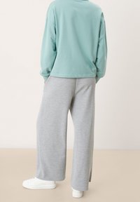 Sudadera de gran tamaño en azul claro combinada con pantalones de chándal de pierna ancha en gris jaspeado. Ambas prendas tienen una textura suave y un ajuste relajado.