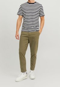 Koszulka na krótki rękaw w paski w kolorze granatowym i białym, zestawiona z oliwkowozielonymi chinosami i białymi trampkami, cechująca się luźnym krojem i prostym designem.