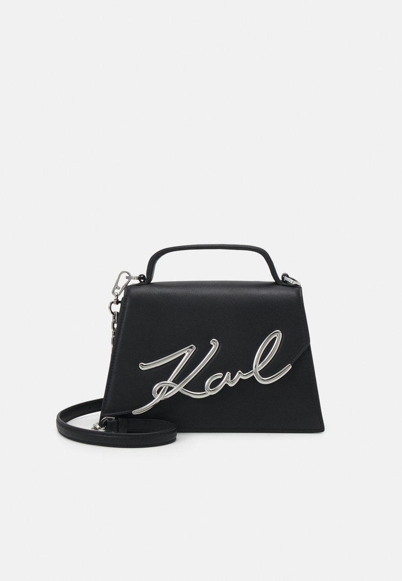 Borsa a mano in pelle nera con un design strutturato, caratterizzata da un accento in argento con la firma "Karl", una maniglia superiore e una tracolla staccabile.