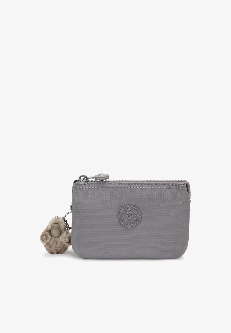 Grey nylon wallet with a smooth texture, zip closure, and a circular logo. Features a furry charm attached to the zipper.