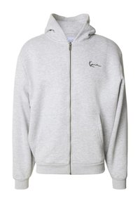 Šedá mikina na zips vyrobená z mäkkého materiálu, s predným vreckom a malým vyšívaným logom na ľavej hrudi. Kapucňa so nastaviteľnou šnúrkou.