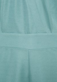 Nabij opname van lichtblauwe stof met details van naden en tailleband, waarbij textuur en stitching op een kledingstuk zichtbaar zijn.