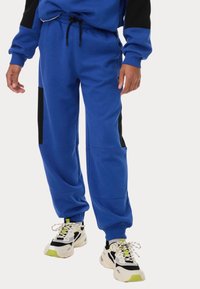Blå sweatpants i mjukt tyg, med svarta detaljer, elastisk midja med dragsko och en avslappnad passform med sidofickor.