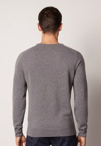 Grau pullover aus weichem Strickstoff. Mit langen Ärmeln, Rundhalsausschnitt und geripptem Saum. Einfaches Design mit minimaler Detailgestaltung.