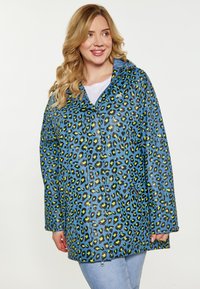 Ľahký modrý pršiplášť s čierno-zeleným leopardím vzorom, obsahujúci zips, kapucňu a dva bočné vrecká. Hladký, lesklý povrch.