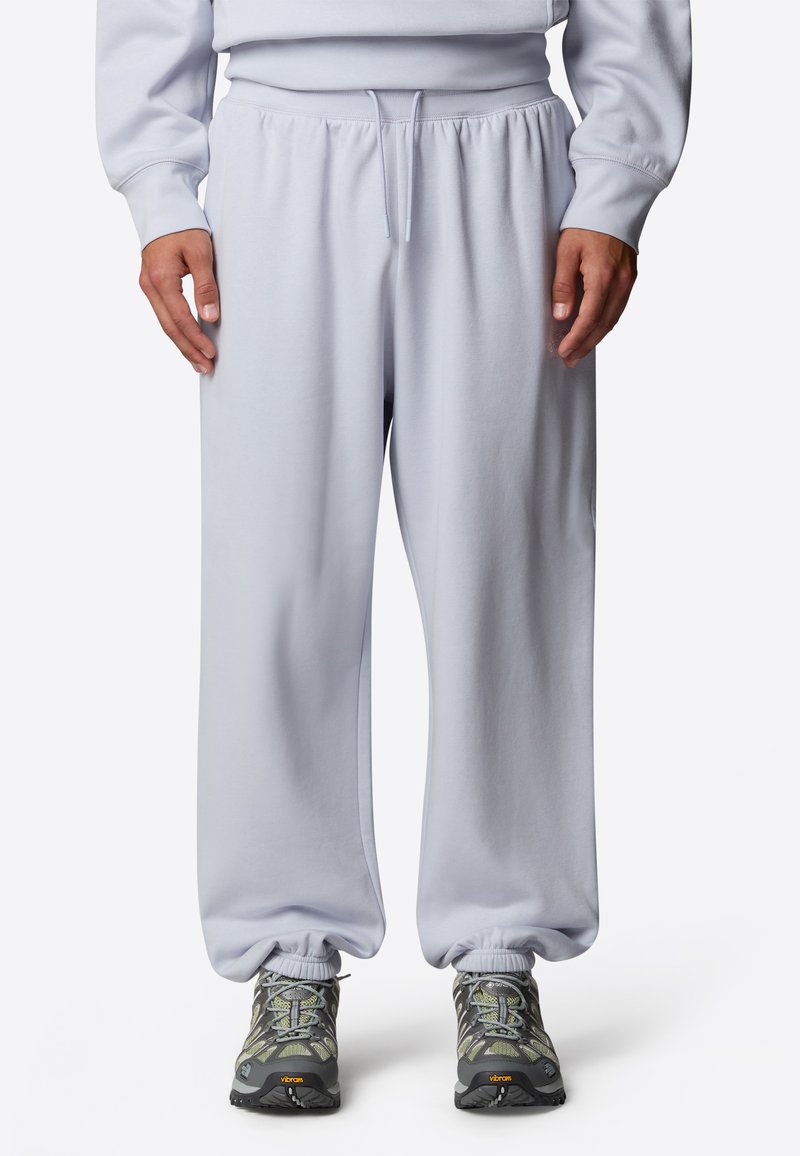 Ljusgrå sweatpants med elastisk midjeband och dragsko. Manschetter vid anklarna. Matchas med mörkgrå sneakers med gröna detaljer.