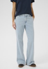 Vaaleansiniset leveät farkut, jotka on valmistettu denimestä, klassisella viiden taskun suunnittelulla, vyölenkeillä ja hieman haalistuneella pinnalla.