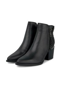 Botas de cuero negro hasta el tobillo con punteras puntiagudas, tacones en bloque, cremalleras laterales y detalles decorativos de tachuelas en el panel trasero.