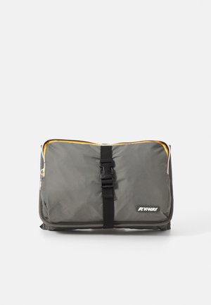 Borsa impermeabile grigia con un accento di cerniera gialla e arancione. Presenta una fibbia nera centrale e un'etichette con logo sul davanti. Forma rettangolare.