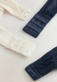 Två behåremmar i beige och mörkblått. Den beiga remmen har sex knäppningar med hysk och ögla; den mörkblå använder tyg med strukturerade detaljer och har tre knäppningar.