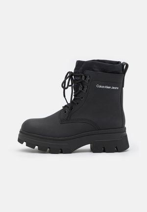 Bottes imperméables noires avec une tige haute, un bout rond, une semelle en caoutchouc texturée, un laçage à l'avant et un détail logo sur le côté.