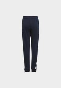 Pantaloni della tuta blu navy con una vestibilità affusolata, cintura elastica e strisce bianche ai lati. Tessuto morbido con polsini a coste sulle caviglie.