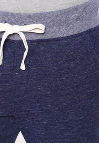 Marineblaue Jogginghose aus strukturiertem Stoff, mit hellgrauem Kordelzug und geripptem Bund.