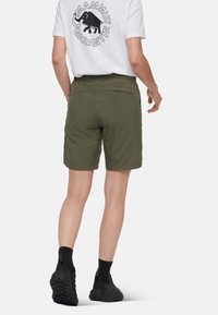 Olivgröna shorts av lätt material, med avslappnad passform, sidofickor och platt midja. Svarta skor med strukturerade sulor.