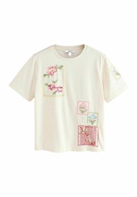 T-shirt en coton crème avec broderie florale multicolore dans un design en patchwork. Manches courtes, col rond, avec divers carrés et rectangles.
