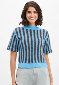 Blauw en bruin gestreepte trui met korte mouwen in een zachte, fuzzy textuur, met een ronde hals en opgerolde mouwen. De lengte van de zoom is iets cropped.