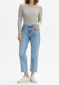 Gray long-sleeve top, fitted design; high-waisted light blue jeans with a straight cut; paired with white sneakers; minimalistic style.