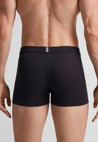Svarta boxershorts i mjukt tyg, med en slät midja och sömlös design. Bakifrån framhävs en tät passform och rena linjer.