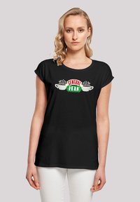 Schwarzes T-Shirt mit kurzen, aufgerollten Ärmeln, das ein farbenfrohes "CENTRAL PERK"-Design und zwei dampfende Kaffeetassen-Grafiken auf der Vorderseite zeigt.