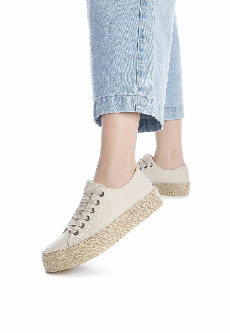 Zapatillas de plataforma de lienzo beige con una suela de yute texturizada, que presentan puntera redonda, diseño de cordones y ojales de metal visibles.