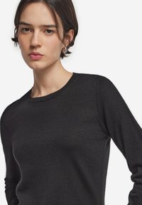 Sort langærmet sweater med rund halsudskæring, lavet af fint, blødt stof; har en tætsiddende silhuet og diskret sømdekoration.