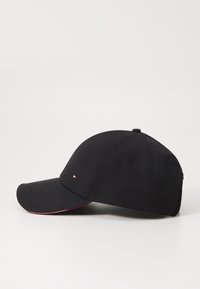 Cappellino da baseball nero in cotone, con visiera curva, schienale regolabile e un piccolo logo davanti. Accento rosso lungo la visiera.