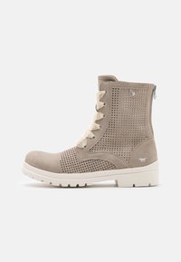 Botas de tobillo beige con cordones, diseño perforado, puntera lisa, cordones beige, cierre de cremallera y suela de goma blanca.