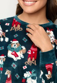 Námořnická fleecová košile s veselým vzorem psů, zahrnující čepice Santa a dárky, s kulatým výstřihem a měkkou texturou.