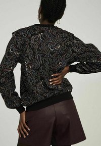 Czarny sweter w wzory z wielokolorowym kwiatowym motywem; posiada prążkowane mankiety i dół, oversize'owe rękawy oraz fakturowaną tkaninę.