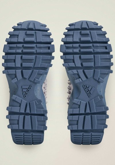 Adidas sporta apavu zoles ar dziļām, neregulārām protektora lēkām; zila krāsa; teksturēta virsma; izcils logo uz katras zoles.