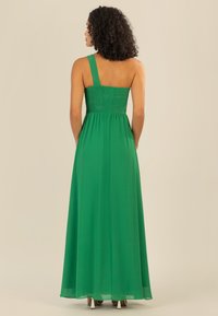 Grünes, knöchellanges Kleid mit einem Schulterträger und einem gesmokten Oberteil. Hergestellt aus leichtem Stoff mit einer glatten Textur.