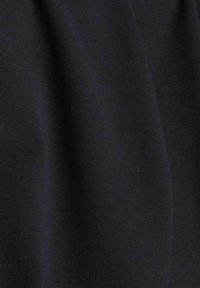 Detailní záběr černé ribované látky s jemnými vertikálními linkami a subtilními vráskami.