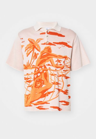 Gebreide polo in licht perzik met een oranje grafisch ontwerp dat een strandscene afbeeldt. Bevat een kraag en drie knopen. Casual pasvorm.