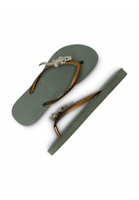 Des tongs avec un semelle en gris texturé, des lanières marron avec un accent reptile. Le design est fonctionnel et audacieux avec des détails remarquables.