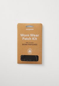 Patagonia Worn Wear Patch Kit in a rectangular brown cardboard packaging with a transparent window, featuring white text and black gear patches inside.