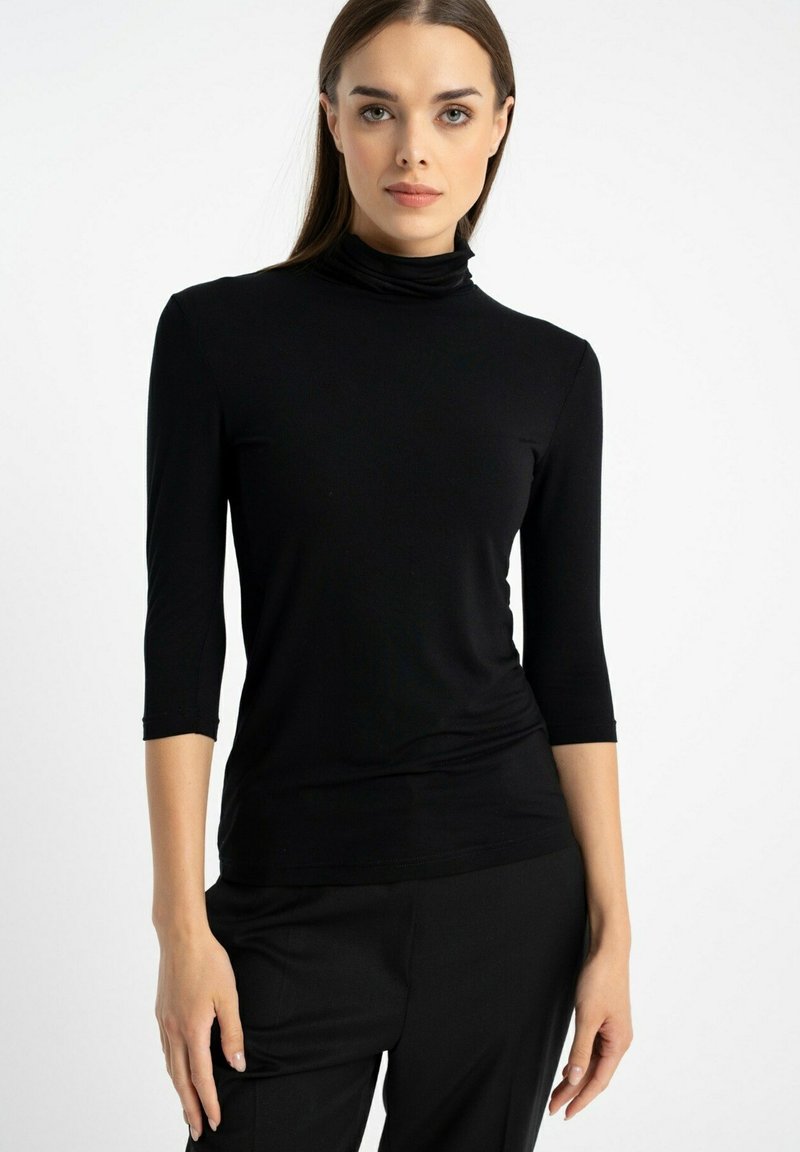 Czarna, długosleeve'owa bluzka z golfem, wykonana z miękkiego materiału, dopasowany fason z rękawami o długości trzy czwarte i gładką fakturą. Brak widocznych wzorów lub akcentów.