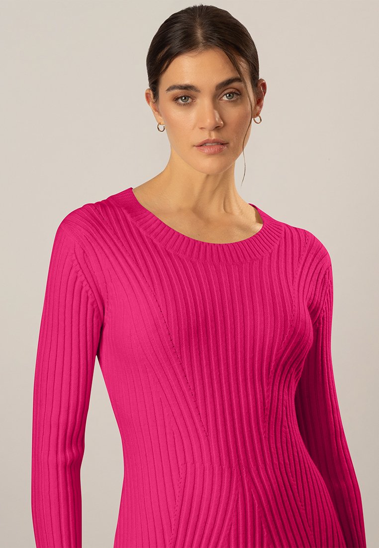 Helles pinkes geripptes Strickkleid mit langen Ärmeln, ausgestattet mit einem runden Ausschnitt und einer taillierten Silhouette, die die vertikale Textur und die Designlinien betont.